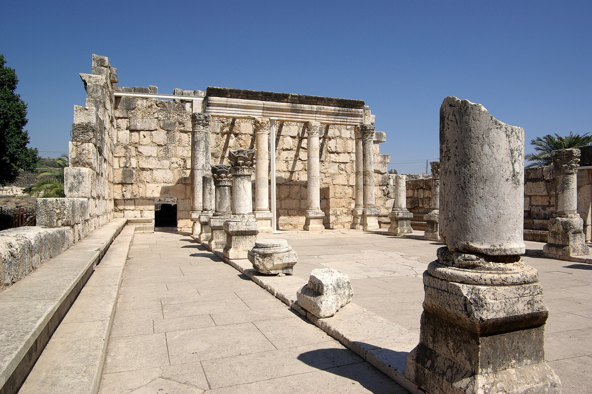 Ruins of the white limestone synagogue at Capernaum with standing columns and carved stonework