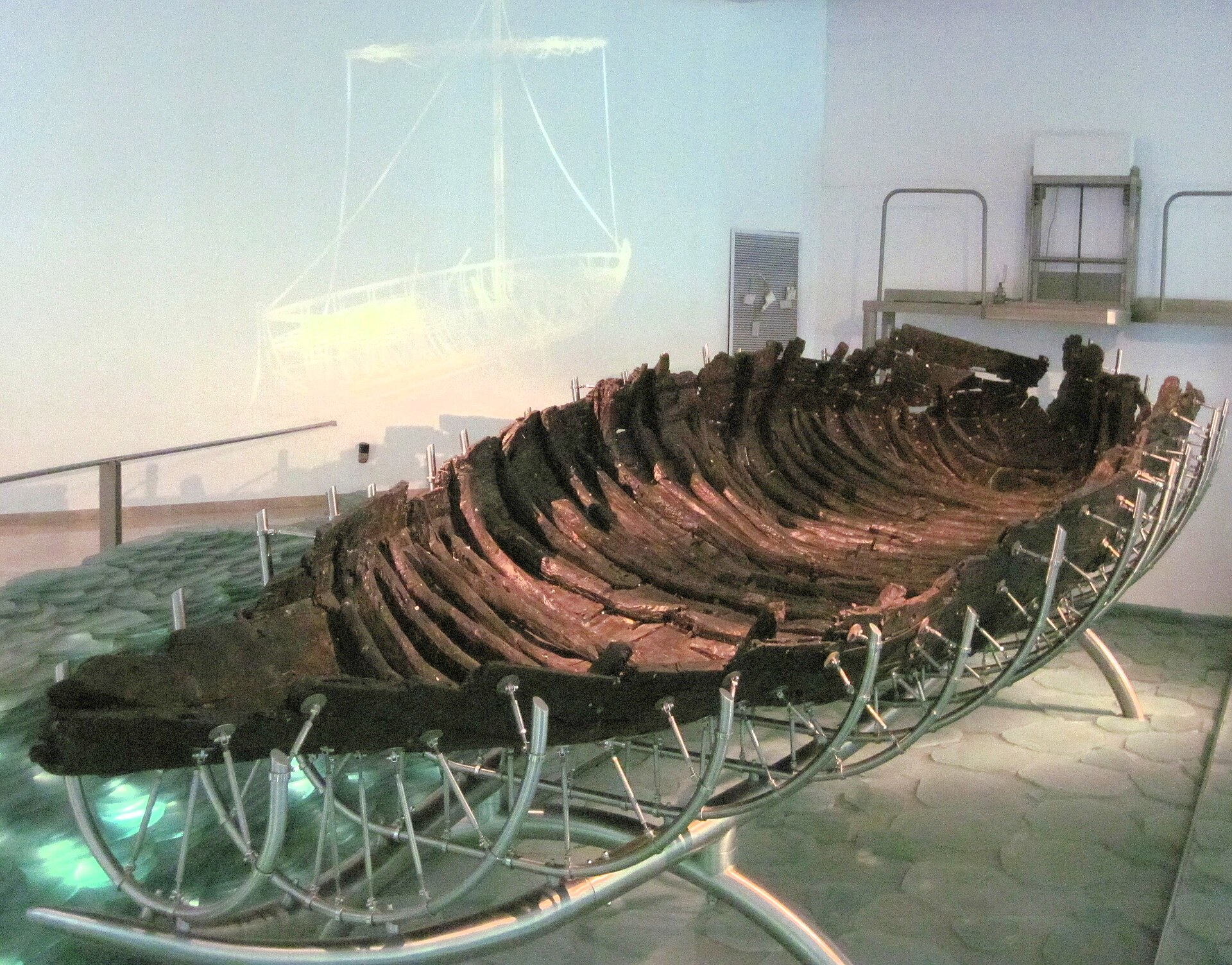 The conserved hull of the ancient Galilee boat mounted on a metal frame inside the Yigal Allon Museum