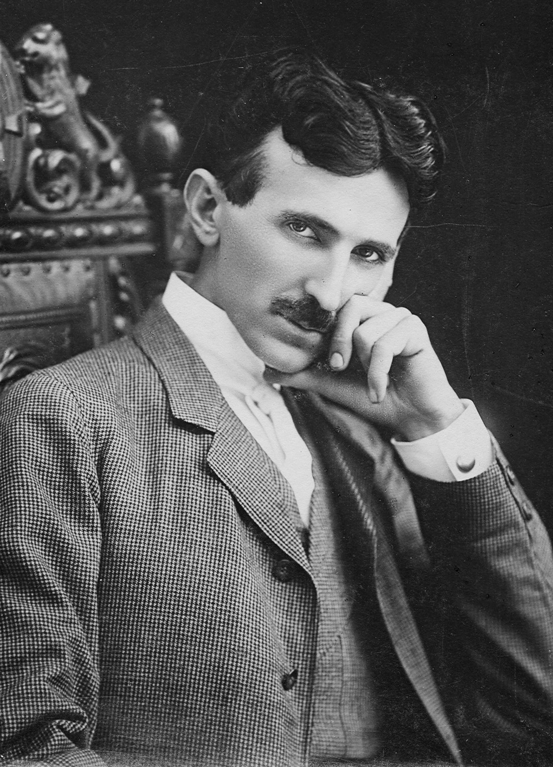 Portrait photograph of Nikola Tesla seated in a chair